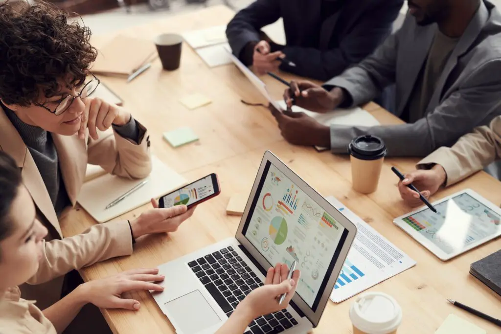 Un groupe de personnes en tenue d’affaires travaillent autour d’une table avec leur appareil numérique